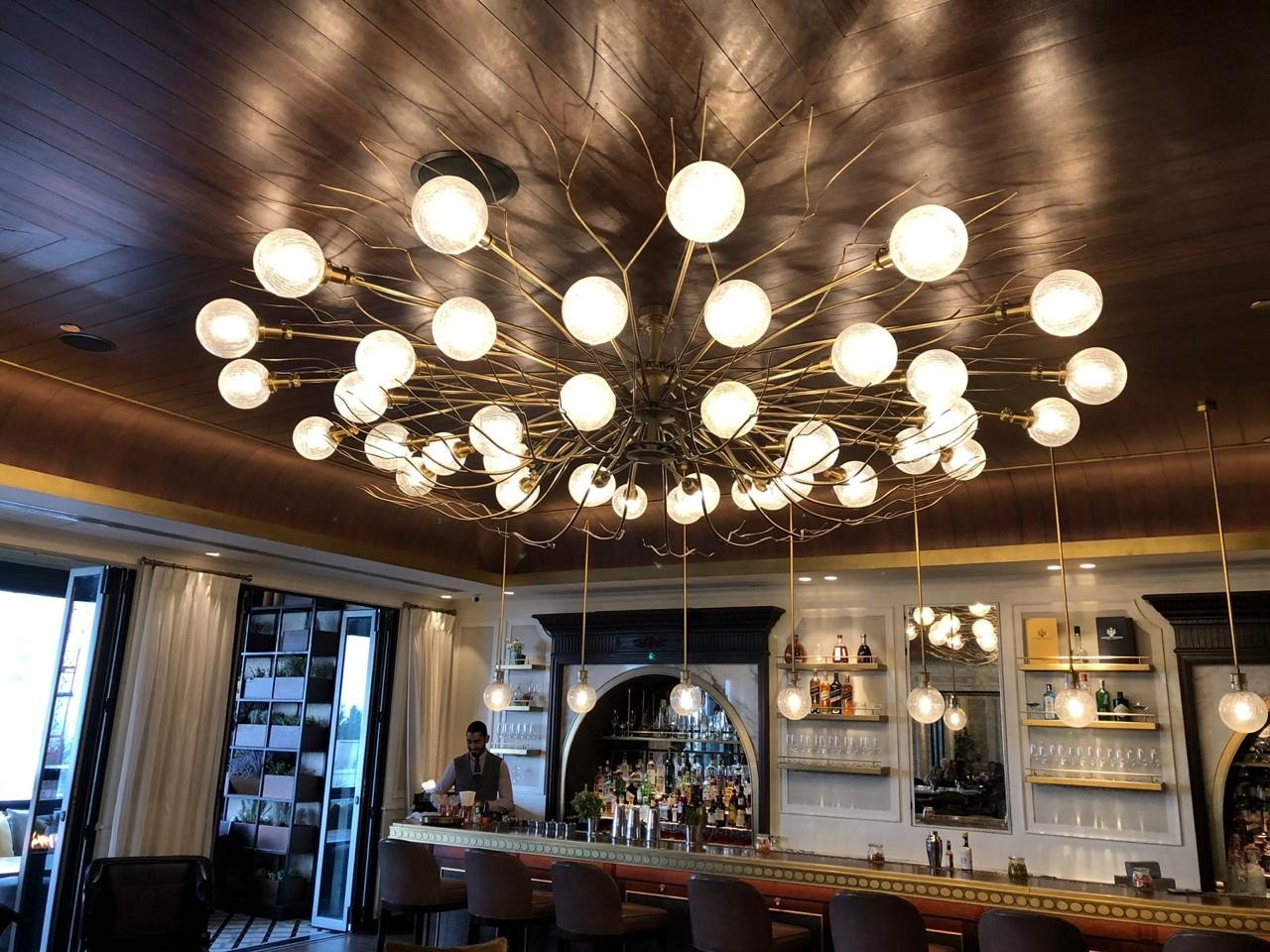 Opal globe chandelier over a bar counter — custom bar lighting by XINCO