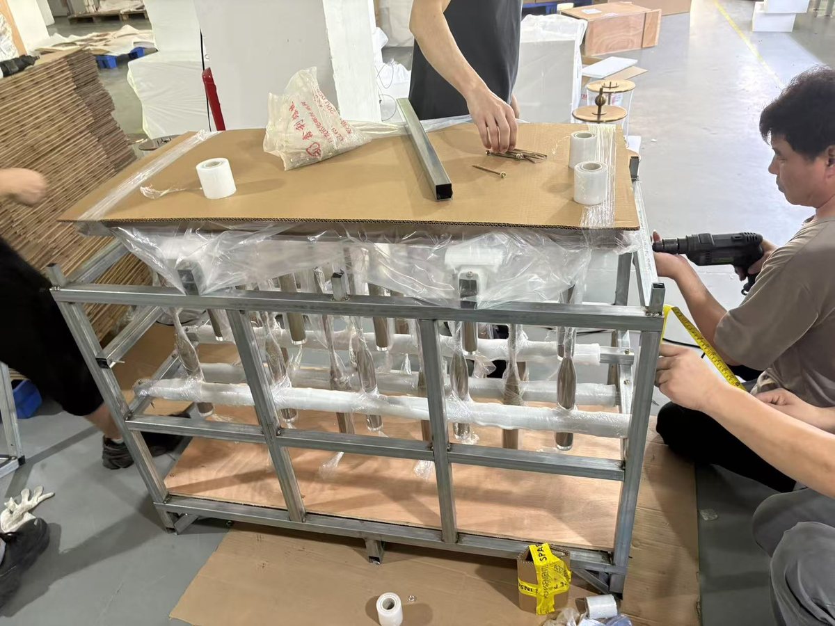 Workers hand-packing foam-wrapped custom fixtures into an export crate