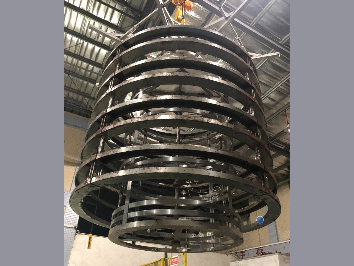 Oversized ring chandelier frame on a crane during workshop dry-fit